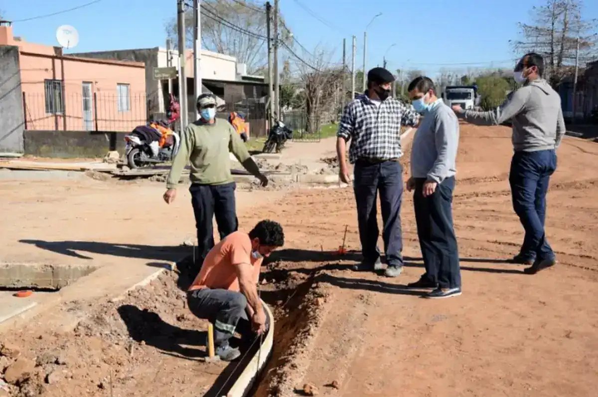 Técnicos y trabajadores supervisan una zanja de servicios en una calle de tierra bonaerense