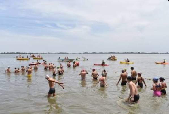 Bañistas, nadadores y personas en kayak practicando actividades recreativas en las aguas de la Laguna de Chascomús.