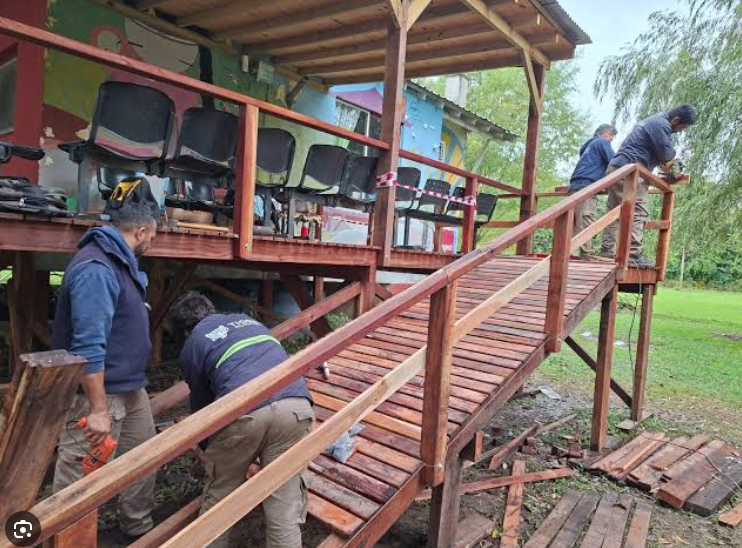 Personal de obra ingresando materiales mediante rampas de madera en un lote del Delta del Tigre.