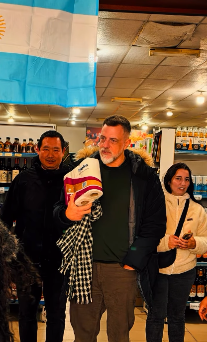 Diego Kravetz sostiene una prenda con colores argentinos durante una visita a un comercio local