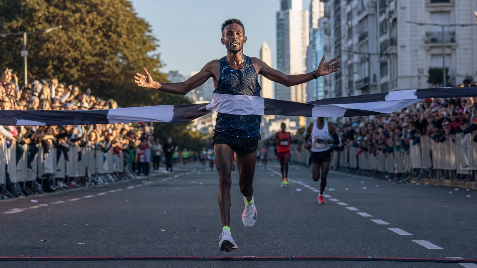 Corredor etíope de élite cruza la meta de una media maratón multitudinaria en Buenos Aires