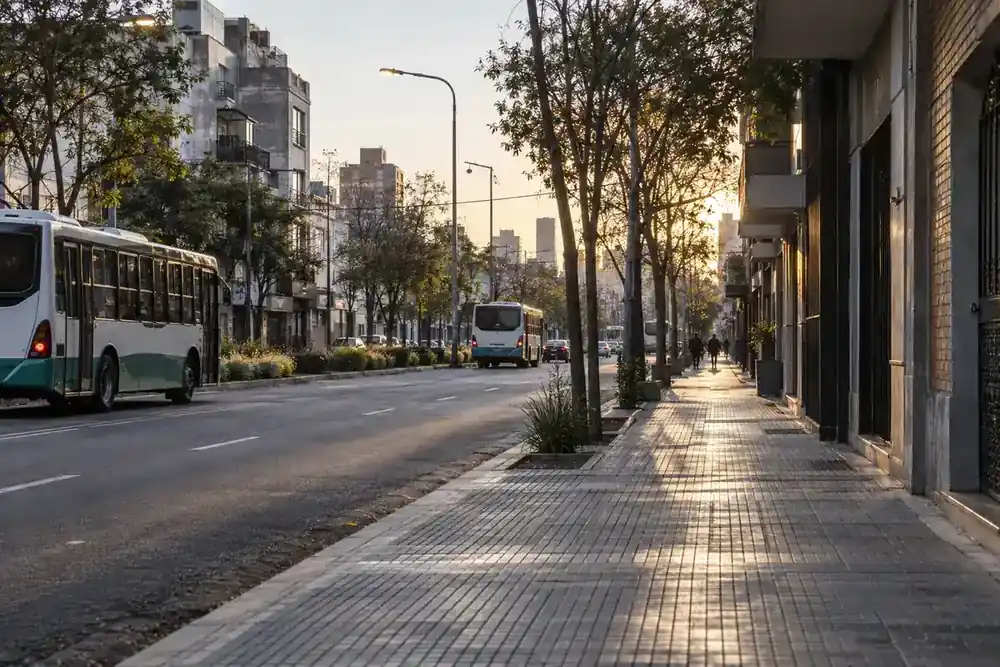 Corredor urbano de Lanús con transporte público, comercios y viviendas al amanecer