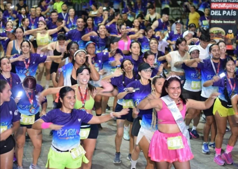 Multitud de participantes en la sesión de calentamiento y baile aeróbico previo a la carrera nocturna RUN Night Neon en Barrancabermeja