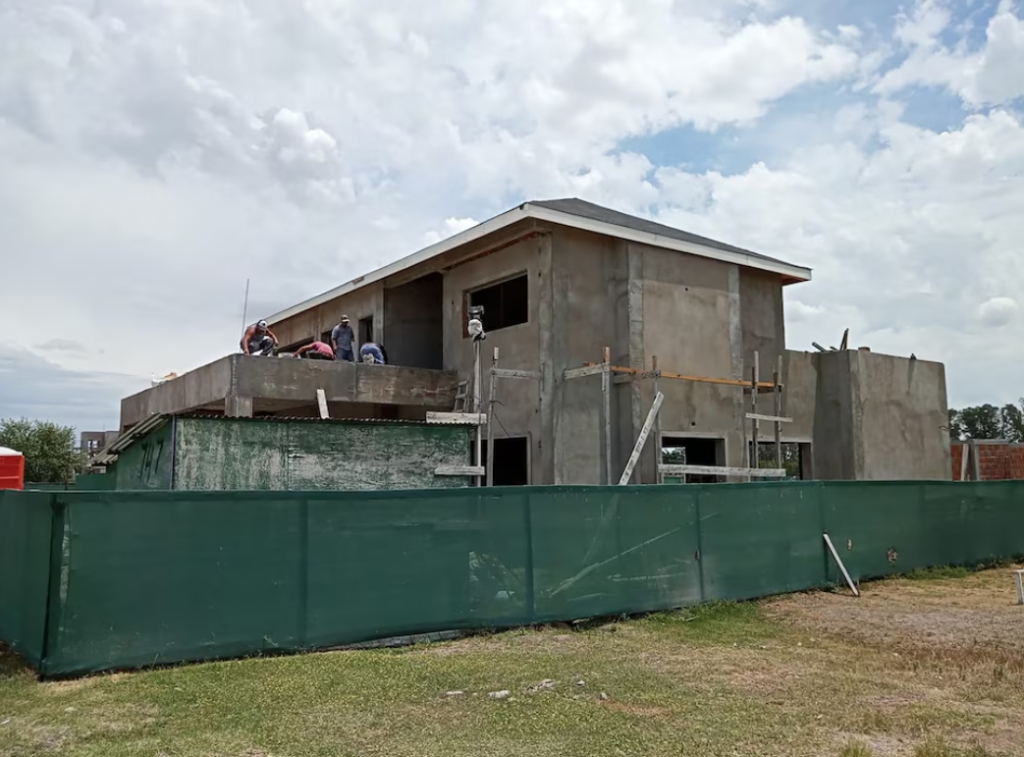 Vista aérea de una vivienda moderna en construcción junto a un espejo de agua, en una urbanización del corredor norte bonaerense