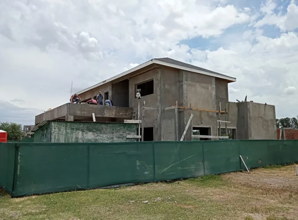 Vista aérea de una vivienda moderna en construcción junto a un espejo de agua, en una urbanización del corredor norte bonaerense